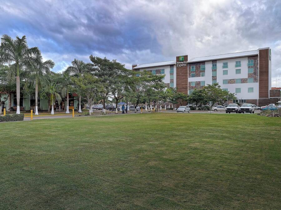 A Holiday Inn Express hotel with a grassy courtyard, palm trees, and a parking area.