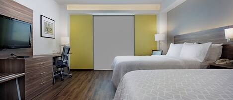 Una habitación de hotel con escritorio, dos camas, televisor y una puerta.