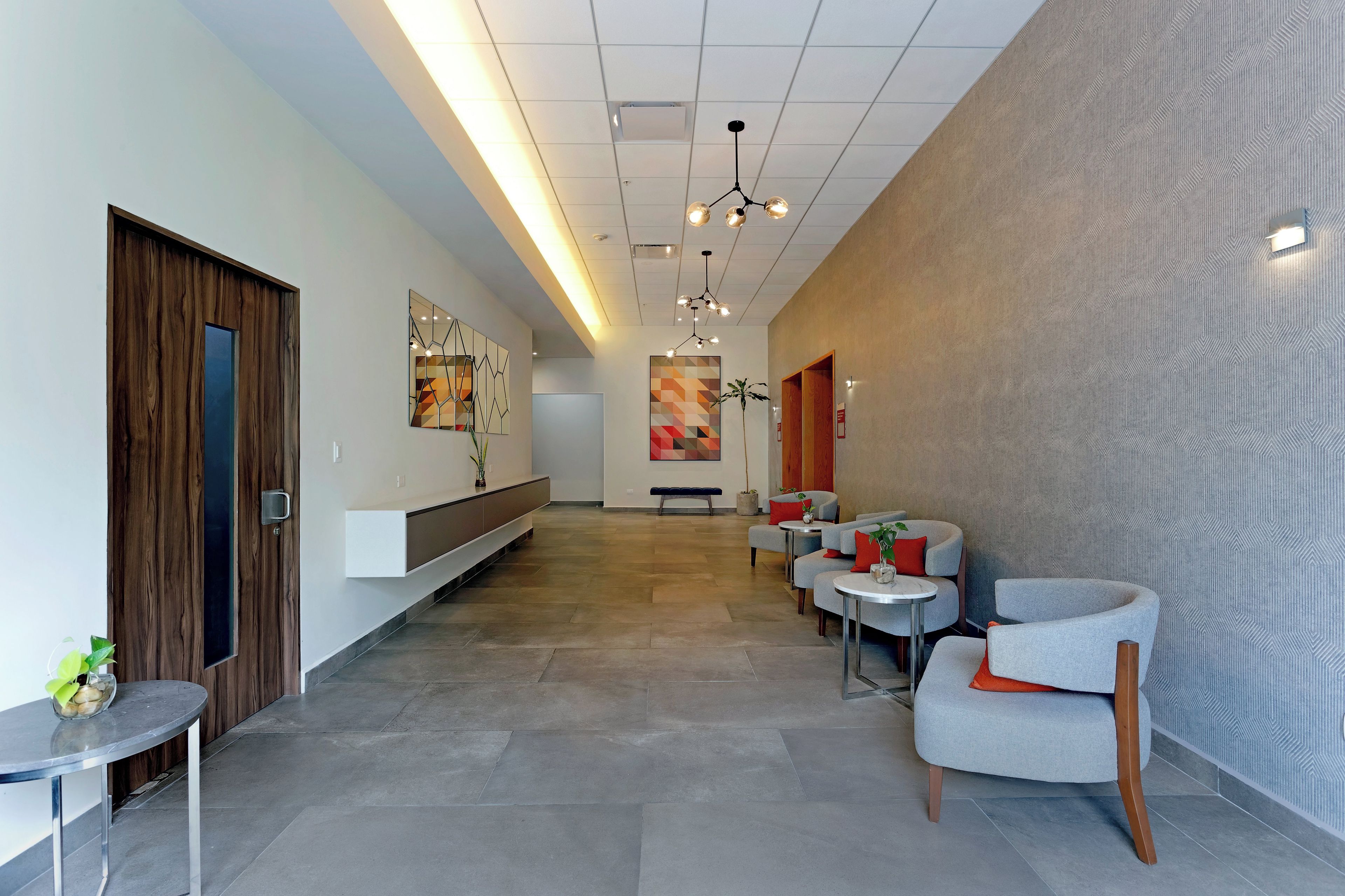 Un lobby moderno con una larga recepción, zona de estar con sillones y una pared con diseño.