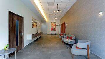 Un lobby moderno con una larga recepción, zona de estar con sillones y una pared con diseño.