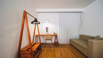 Una habitación con un escritorio de madera, una silla, un sofá y una lámpara colgante.
