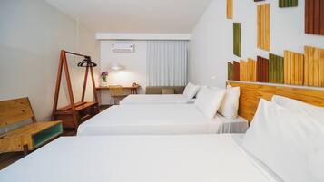 Une chambre d’hôtel avec deux lits, une tête de lit en bois, un bureau avec une chaise et un climatiseur fixé au mur.