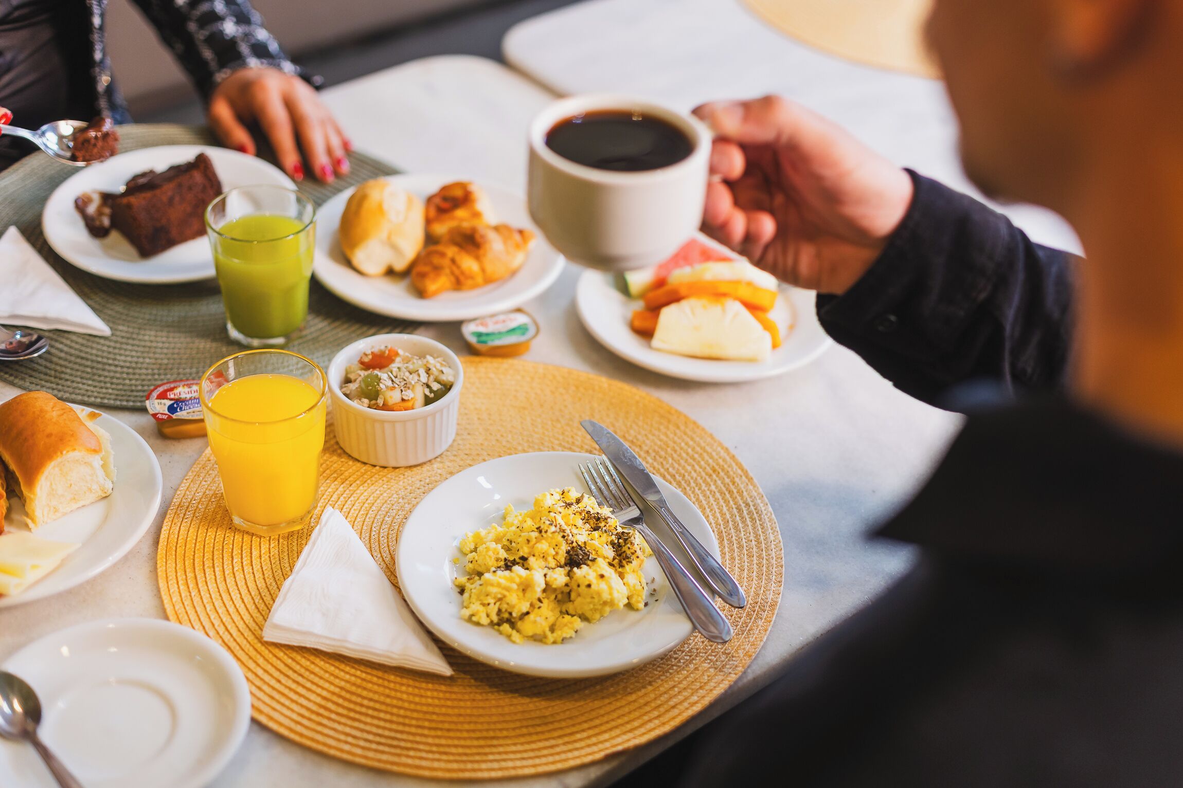 Un desayuno servido con platos de comida, una taza de café y un vaso de zumo de naranja.