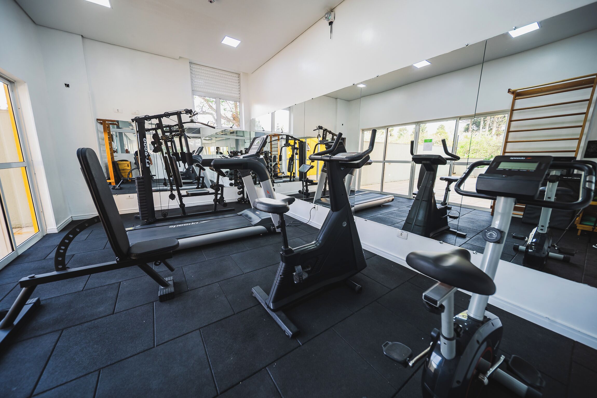 Een fitnessruimte met diverse trainingsapparaten, waaronder loopbanden, een elliptische trainer en krachtapparaten.