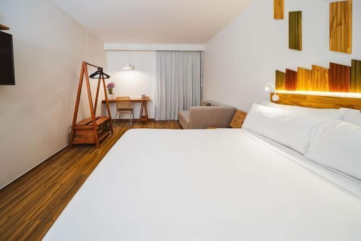 Een hotelkamer met een groot bed, een bureau, een stoel en een televisie.
