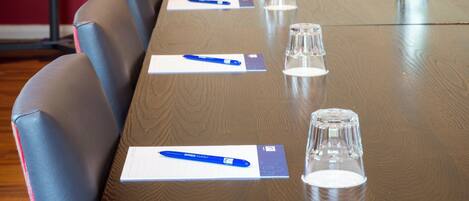 A conference table with chairs, pens, and glasses.