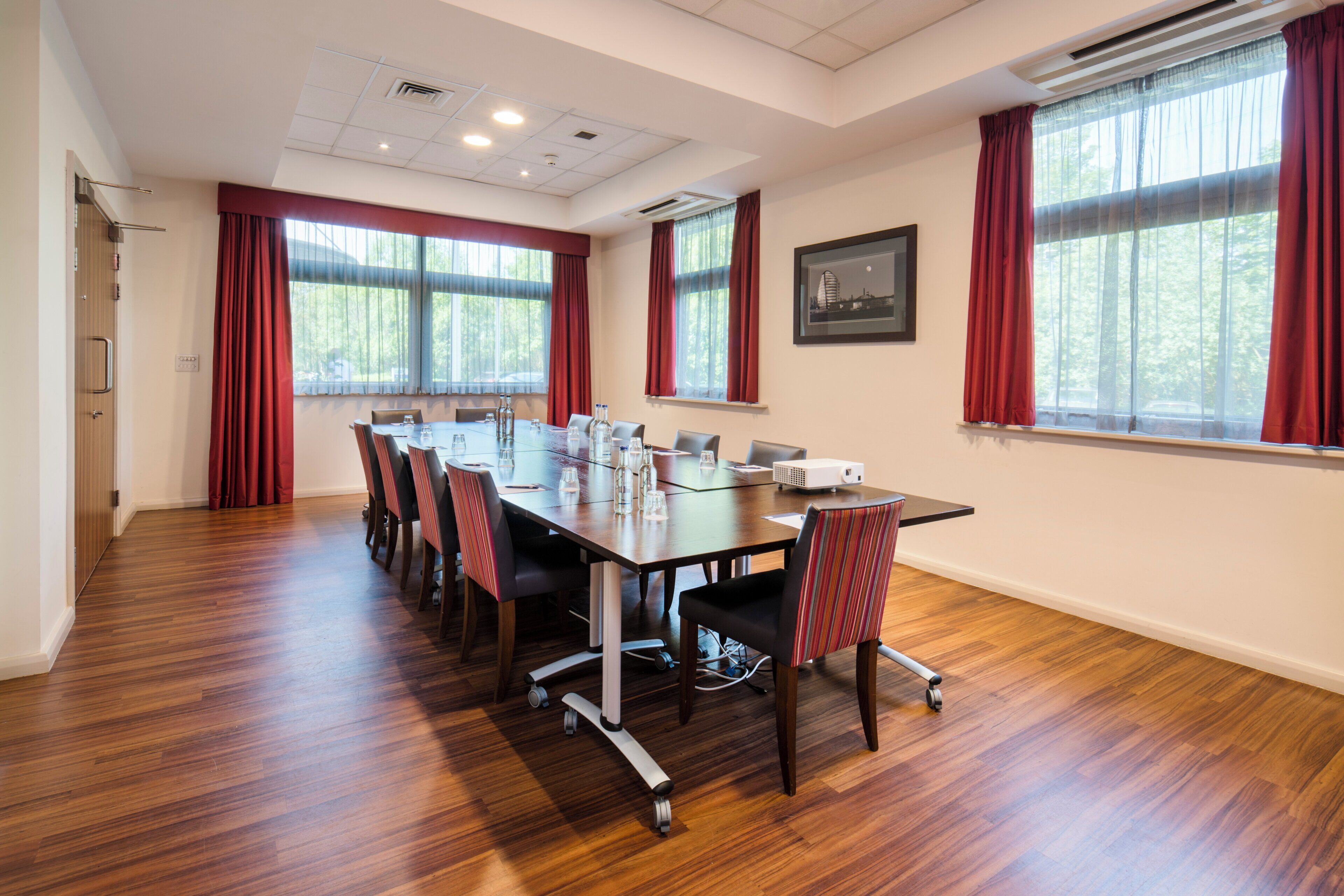 Une salle de conférence avec une longue table, des chaises et un projecteur.