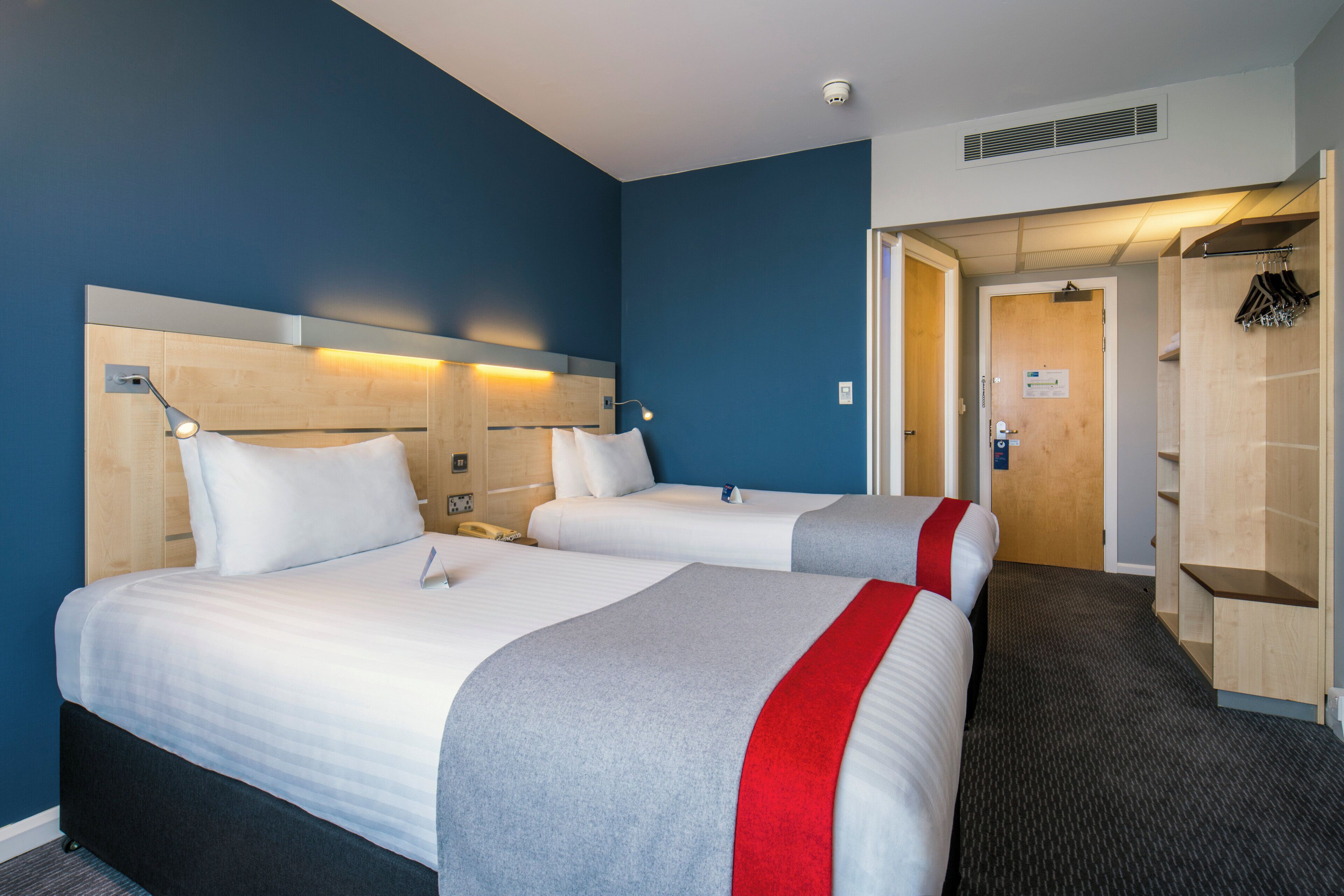 Ein Hotelzimmer mit zwei Betten, einem Kleiderschrank und einer Badezimmertür.