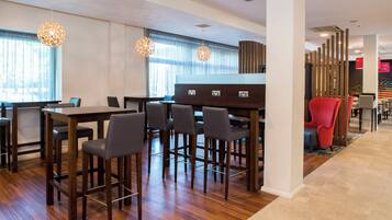 A modern hotel lobby with a bar area, wooden flooring, and pendant lighting.