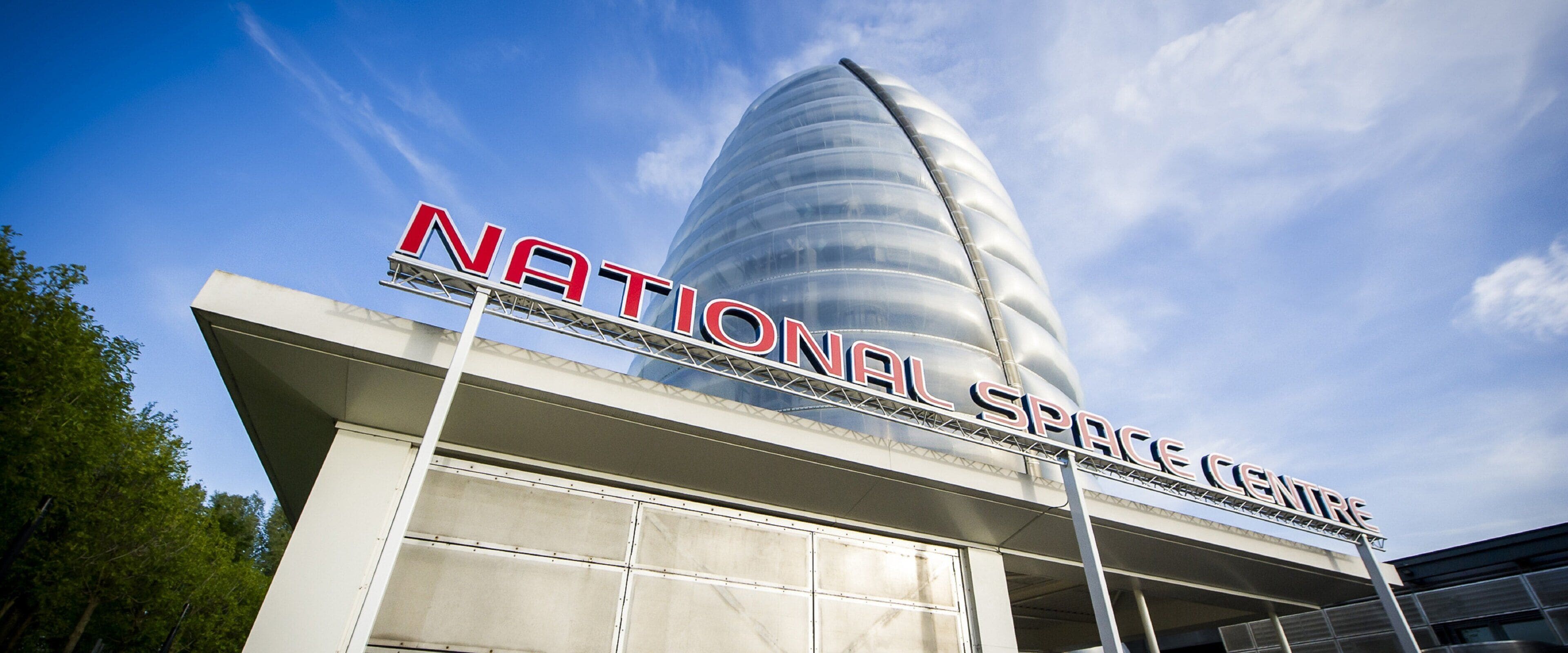 A modern building with a large, curved glass facade and the words 'NATIONAL SPACE CENTER' prominently displayed.