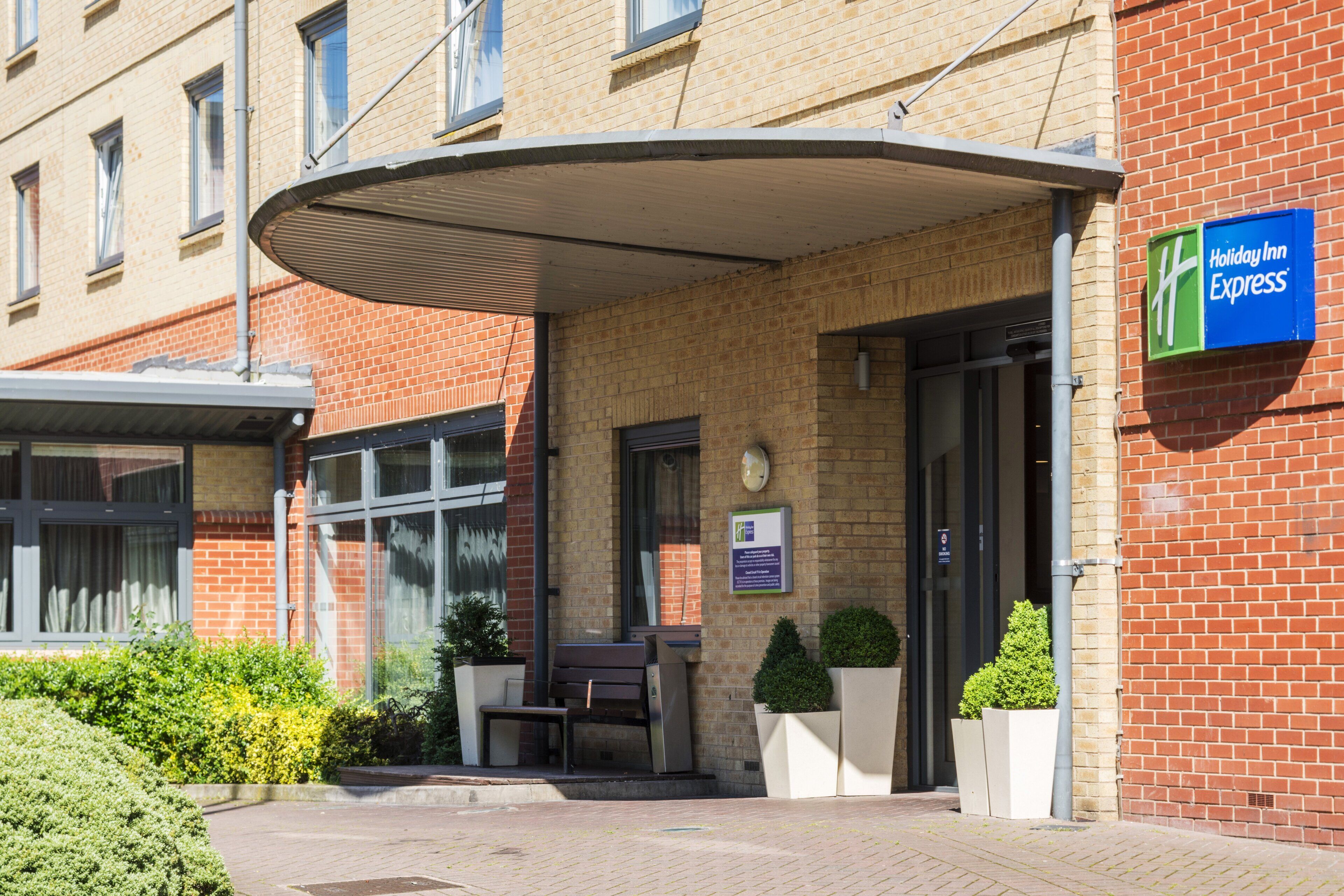 A Holiday Inn Express building with a brick facade, a covered entrance, and a signboard.