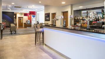 A bar area with a counter, stools, and a variety of liquor bottles.