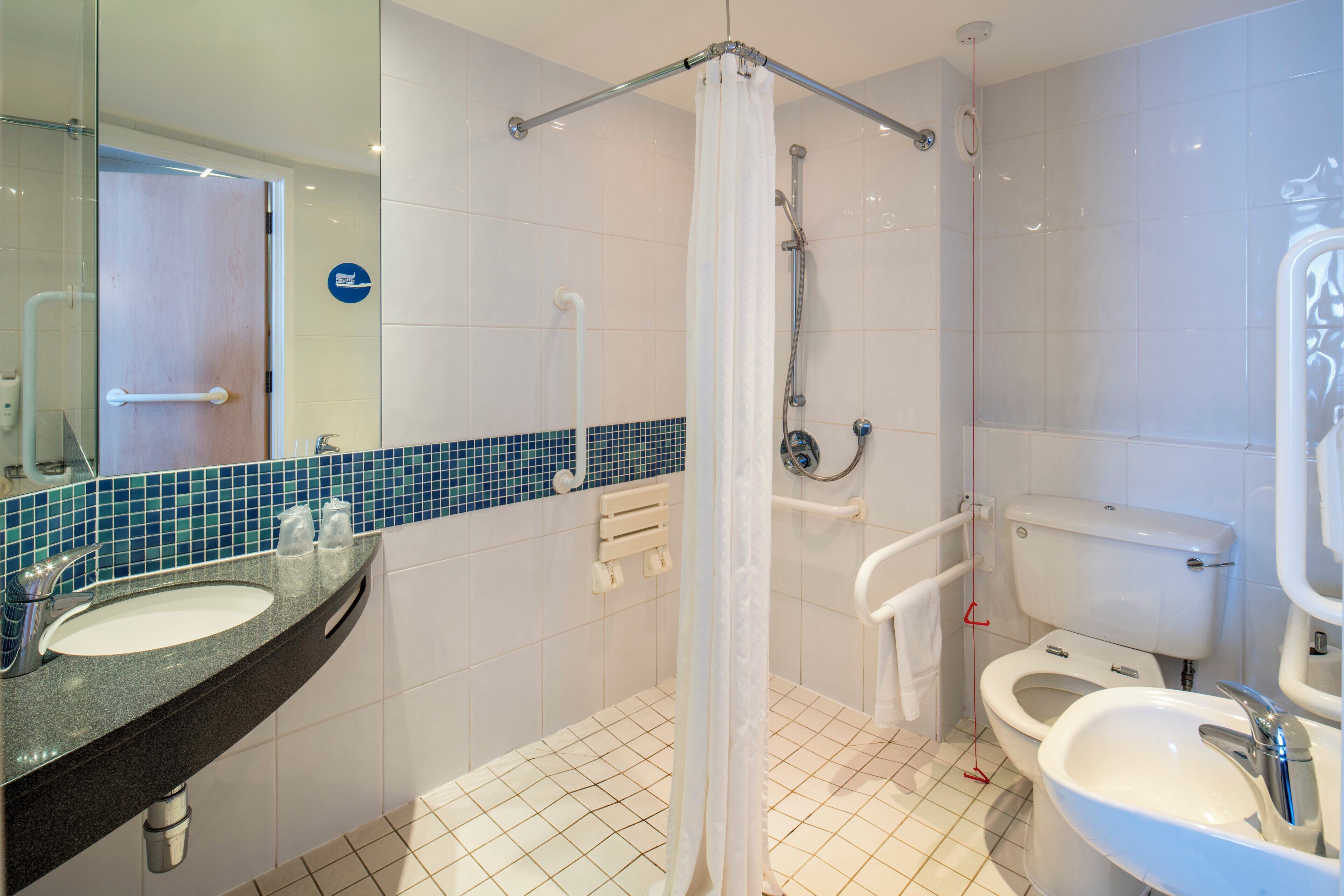 Un baño con ducha, inodoro, lavamanos y espejo.