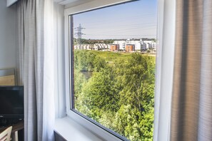A room with a large window overlooking a green area with trees and buildings in the distance. - Holiday Inn Express Leicester - City by IHG (Leicester)