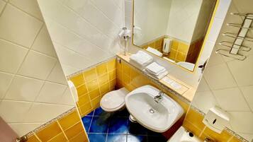 A bathroom with yellow and white tiles, a white sink, a toilet, and a bathtub.