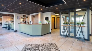 Een moderne hotelentree met een receptiebalie, een bar en zitplaatsen.
