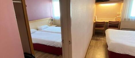 A compact hotel room with two beds, a television, and a small desk area.