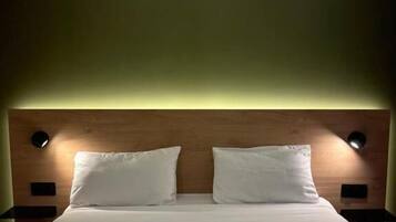 Un lit double avec une tête de lit en bois, deux tables de chevet avec des lampes et un mur vert.