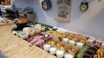Una mesa de buffet con diversos alimentos y un letrero que dice 'GOOD FOOD IS THE SWEETER GOOD FRIENDS'.