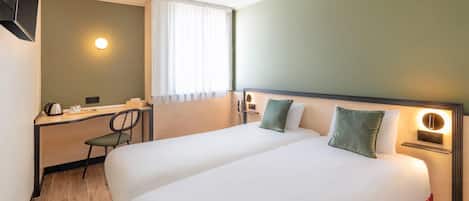 Une chambre d’hôtel avec un lit, un bureau, une chaise, une télévision et une fenêtre avec des rideaux.