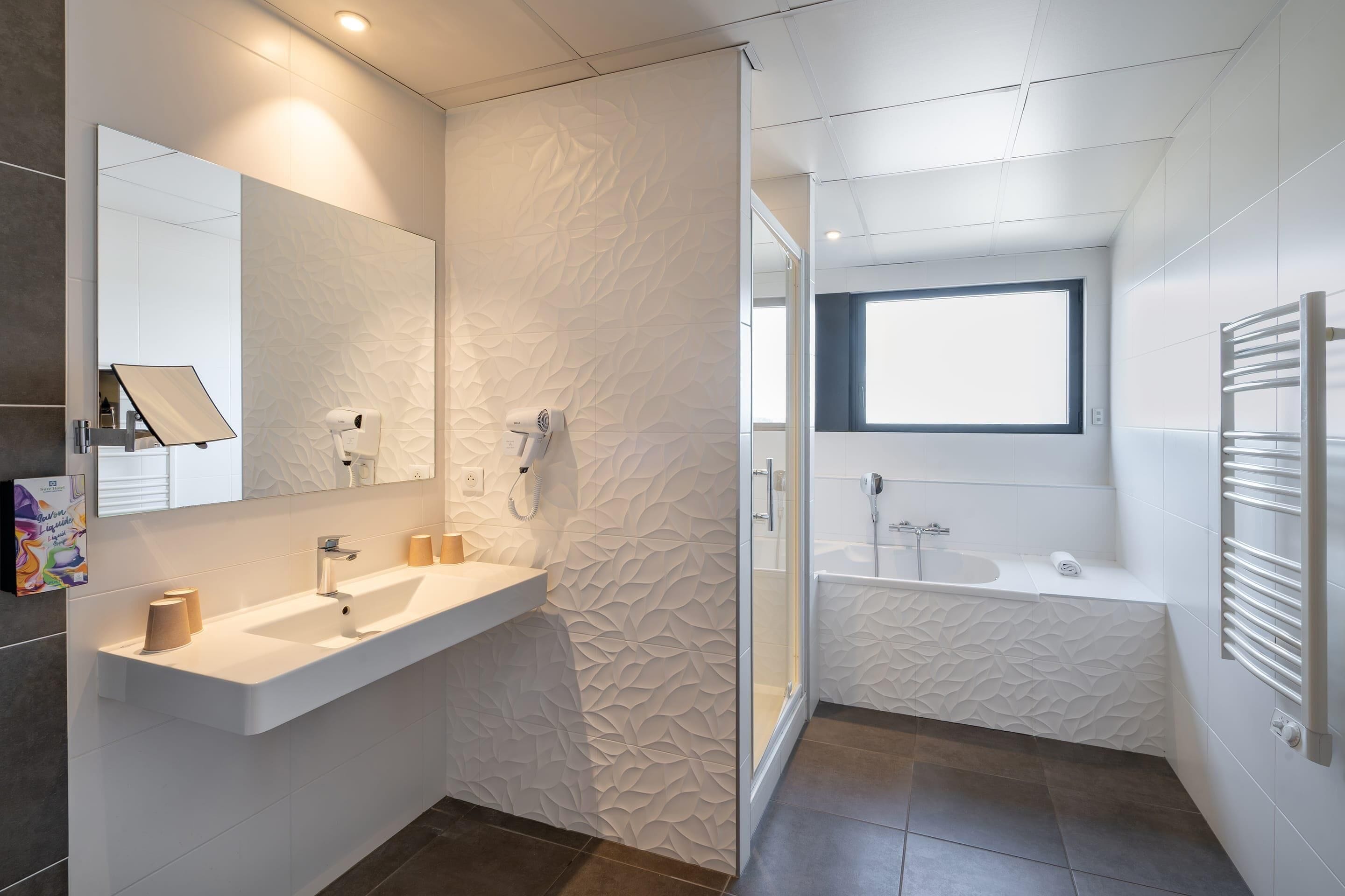 A modern bathroom with a large mirror, a sink, a shower, and a bathtub.