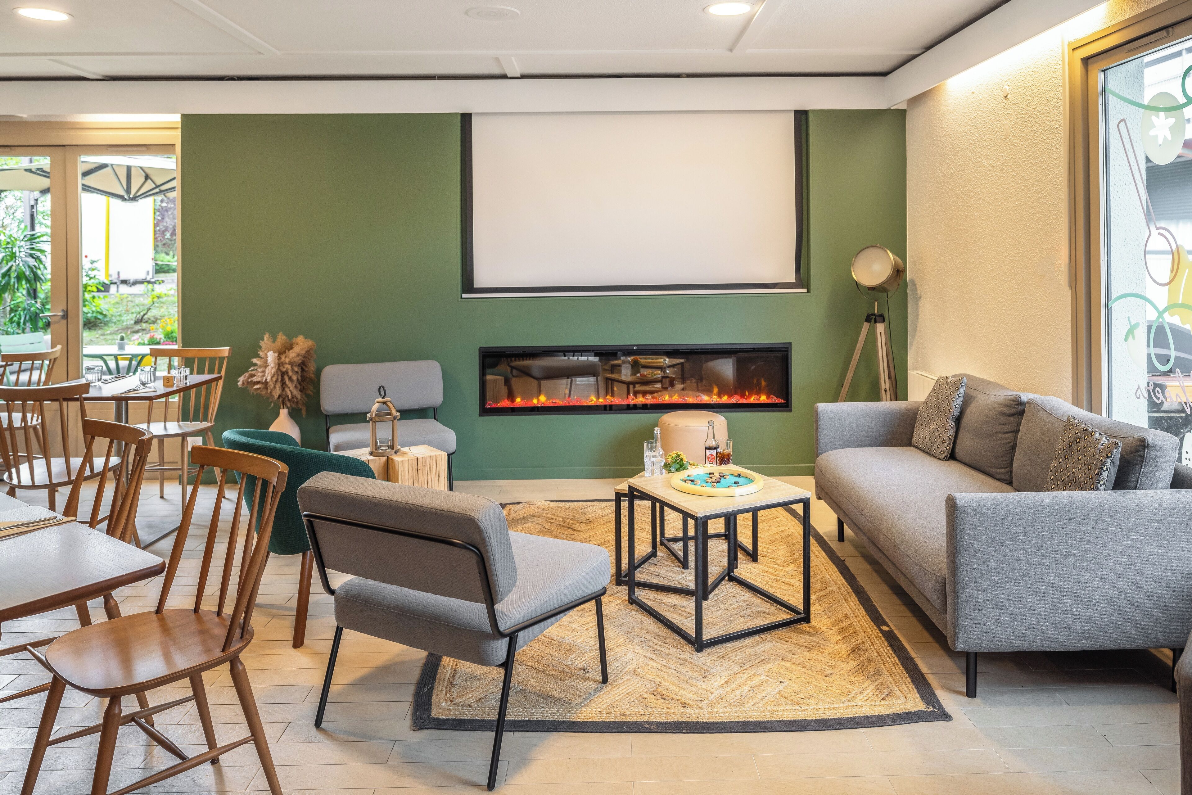 A modern living room with a fireplace, green walls, and a seating area with a sofa and chairs.