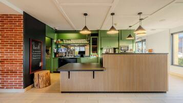 A modern kitchen area with a wooden island, green walls, and pendant lighting.