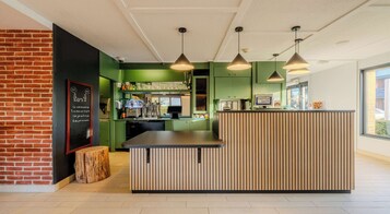 A modern kitchen area with a wooden island, green walls, and pendant lighting.