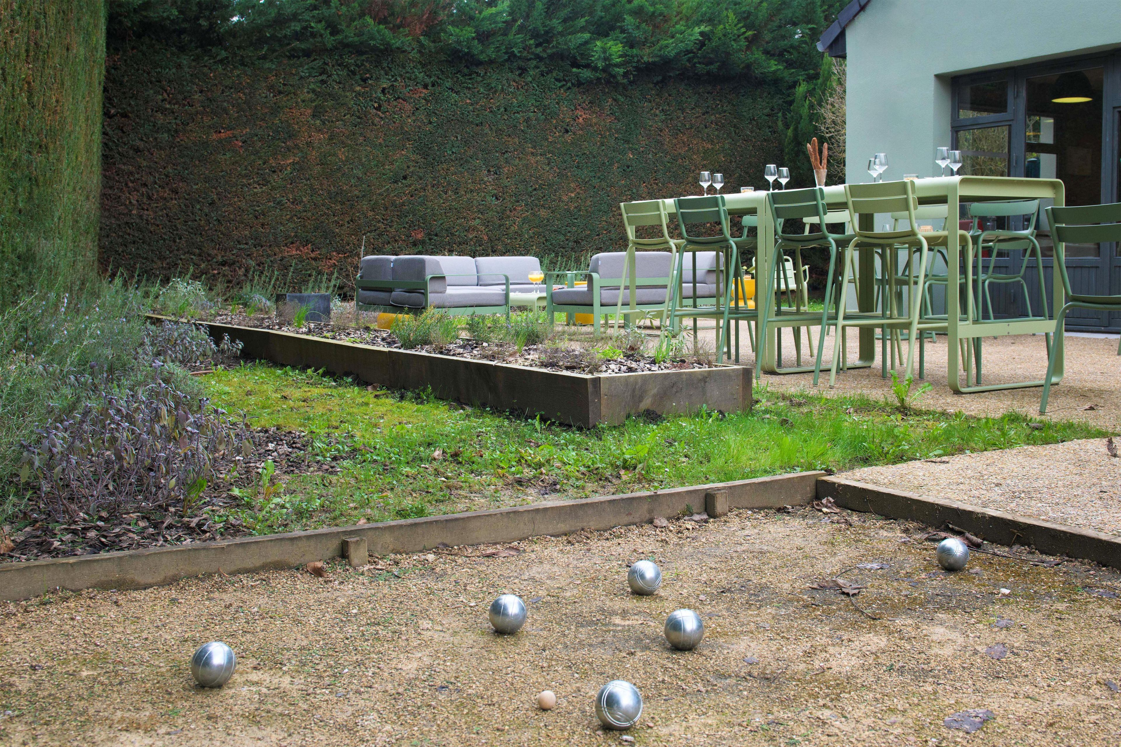 A garden area with a seating arrangement, a table, and a hedge in the background.