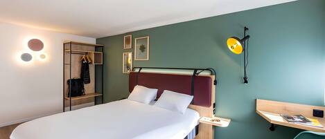 Una habitación de hotel moderna con cama, escritorio, silla y armario.