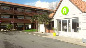 A hotel with a modern design, featuring a prominent green logo on the facade.