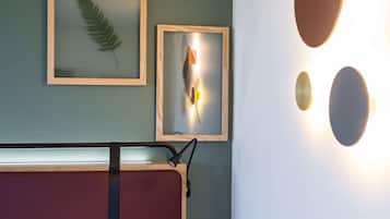 Quarto de hotel com cama, mesa de cabeceira, abajur, obras de arte emolduradas na parede e luminárias fixadas na parede.