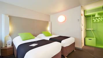 A hotel room with two beds, a green wall, a round light fixture, and a green wardrobe.