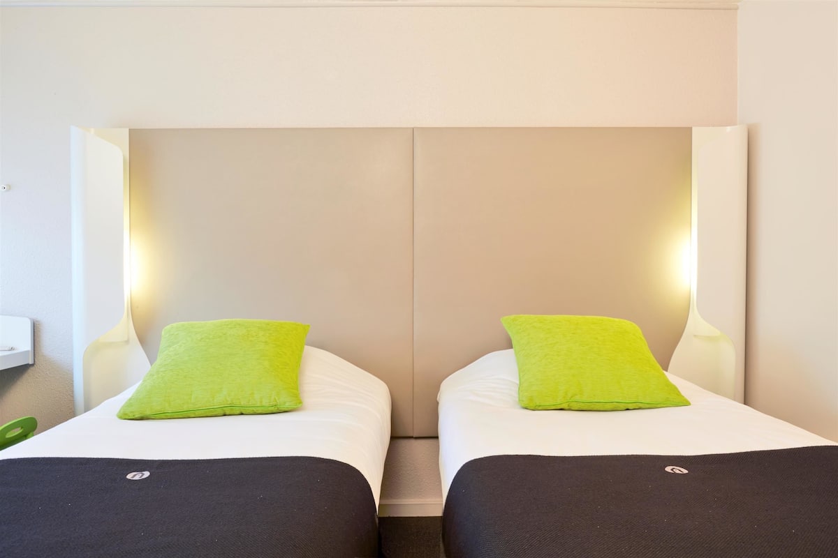 A double bed with two green pillows and a black bedspread.