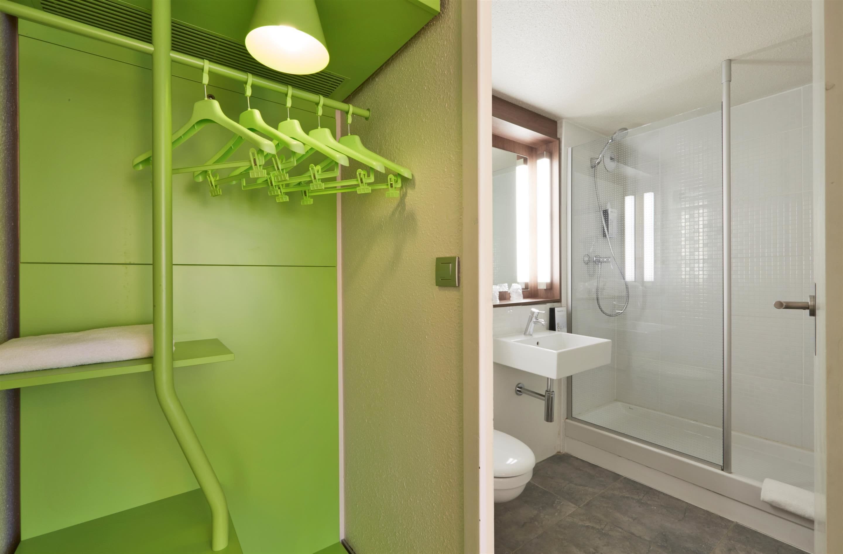 A bathroom with a green wall, a white sink, and a glass shower enclosure.
