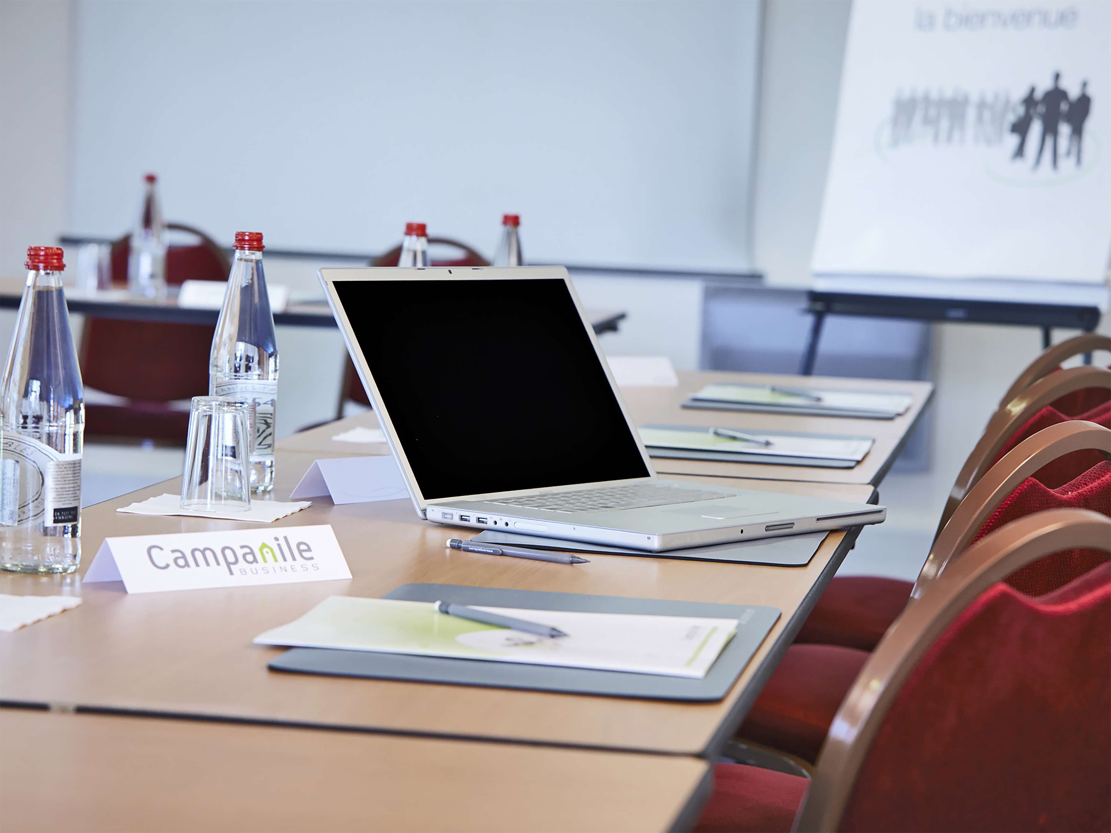 A conference room with a laptop, nameplates, water bottles, and a whiteboard.