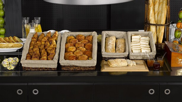 A buffet table with various baked goods, including croissants, bread rolls, and baguettes. - Campanile Lyon Sud - Feyzin (Feyzin)