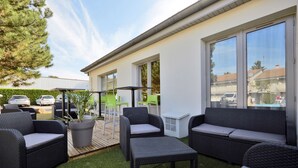 A patio area with wicker furniture, a potted plant, and a view of the street. - Campanile Lyon Sud - Feyzin (Feyzin)