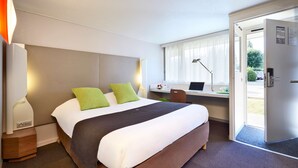 A hotel room with a bed, a desk, a chair, and a door. - Campanile Lyon Sud - Feyzin (Feyzin)