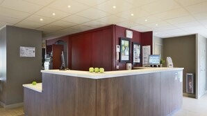 A reception desk with a wooden finish, a digital screen, and a telephone. - Campanile Lyon Sud - Feyzin (Feyzin)
