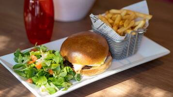 Un sándwich con papas fritas y ensalada en un plato blanco.