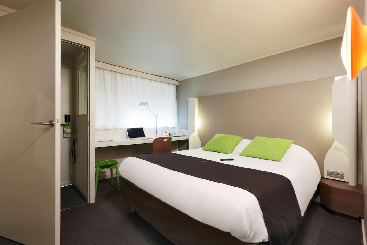 Une chambre d’hôtel équipée d’un lit, d’un bureau, d’une chaise et d’une lampe.