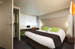 Ein Hotelzimmer mit Bett, Schreibtisch, Stuhl und Lampe.