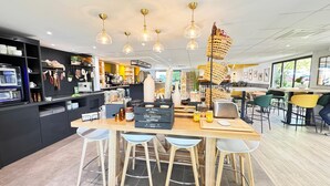A modern cafe interior with a wooden bar, hanging wicker baskets, and pendant lighting. - Campanile L'Isle d'Abeau - Bourgoin Jallieu (L'Isle-d'Abeau)