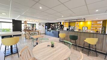 A modern cafe with a bar area, wooden tables, and chairs.