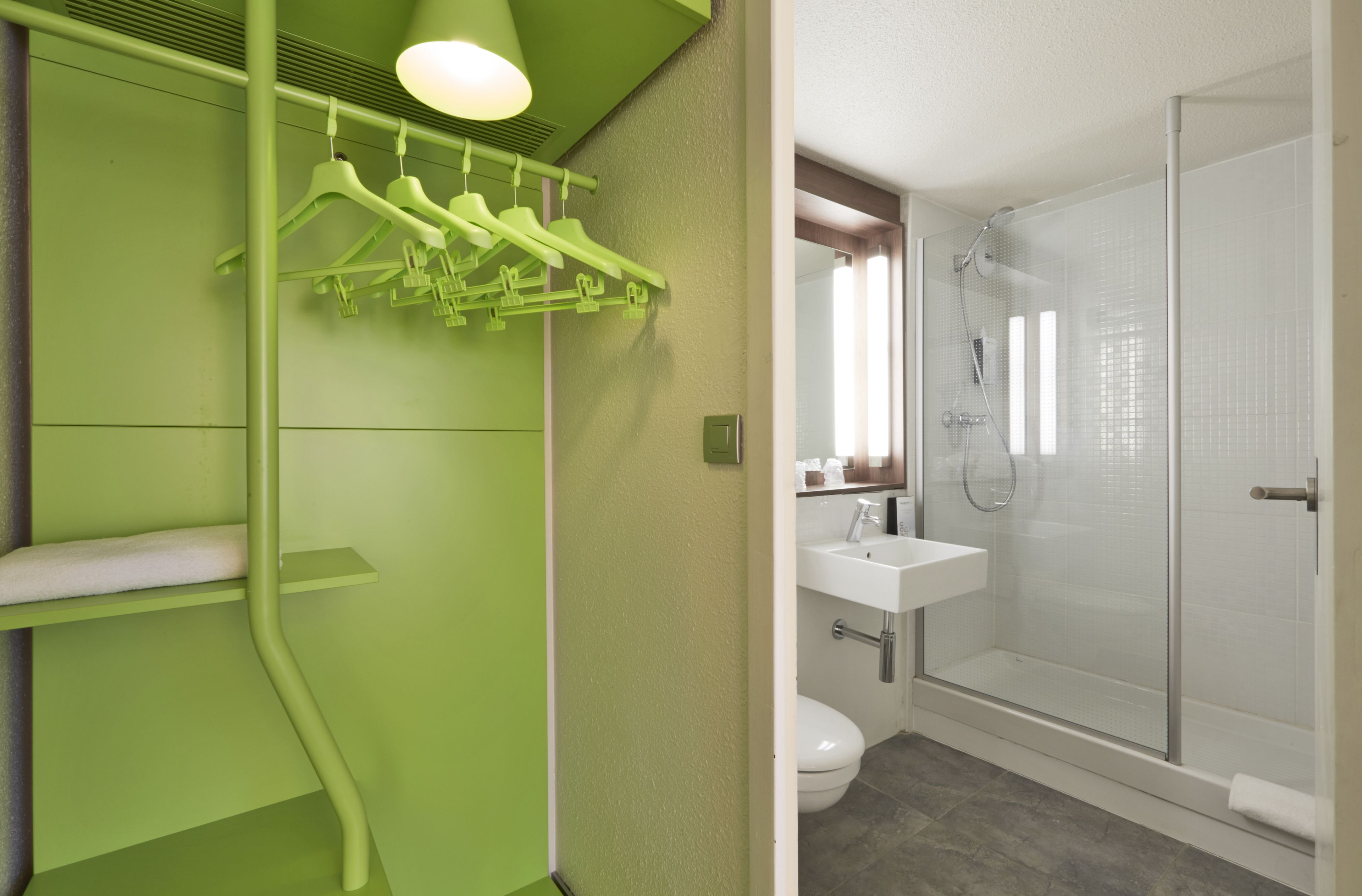 A bathroom with a green wall, a white sink, and a glass shower enclosure.