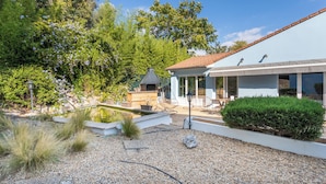 Una casa moderna con un patio, mobiliario exterior y una piscina pequeña.