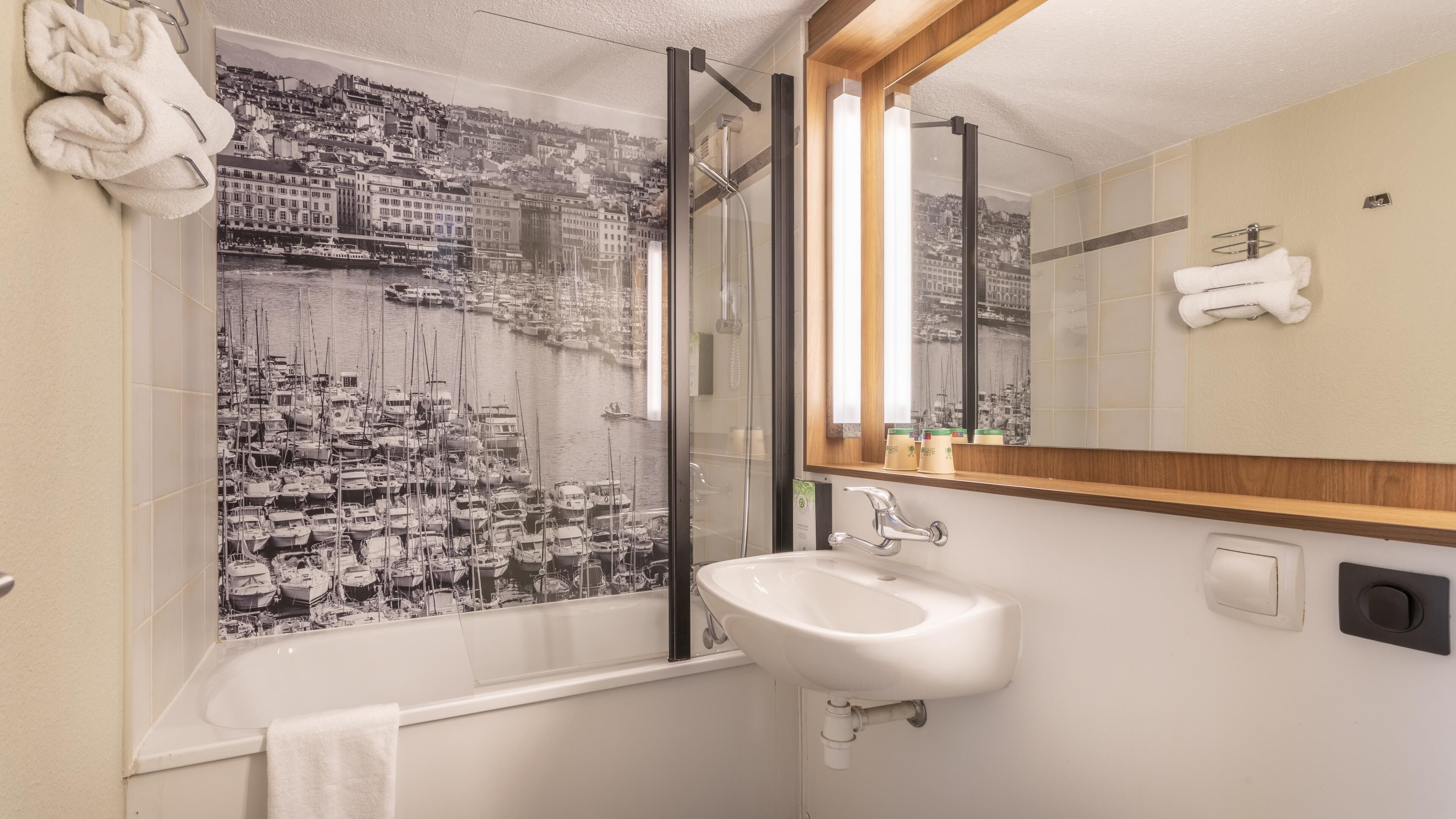 Une salle de bain avec un grand miroir, une baignoire et un lavabo.