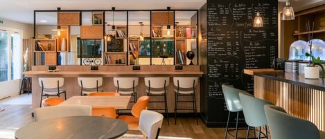 Un área de bar moderna con un menú en una pizarra, sillas blancas y una barra de madera.