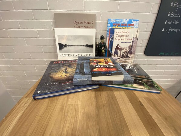 A table with books and a signboard against a brick wall.